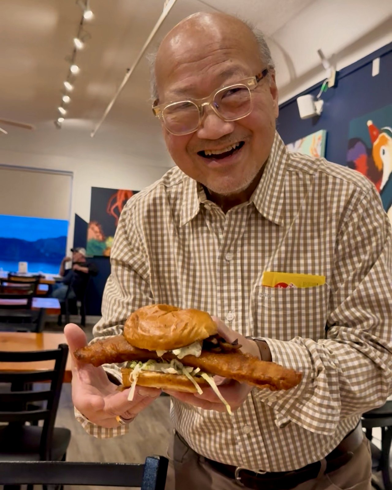 Tom, OV Burger Bar co-founder, holding up The Holy Ship signature fish sandwich in the dining room at OV Burger Bar in Prince Rupert, BC