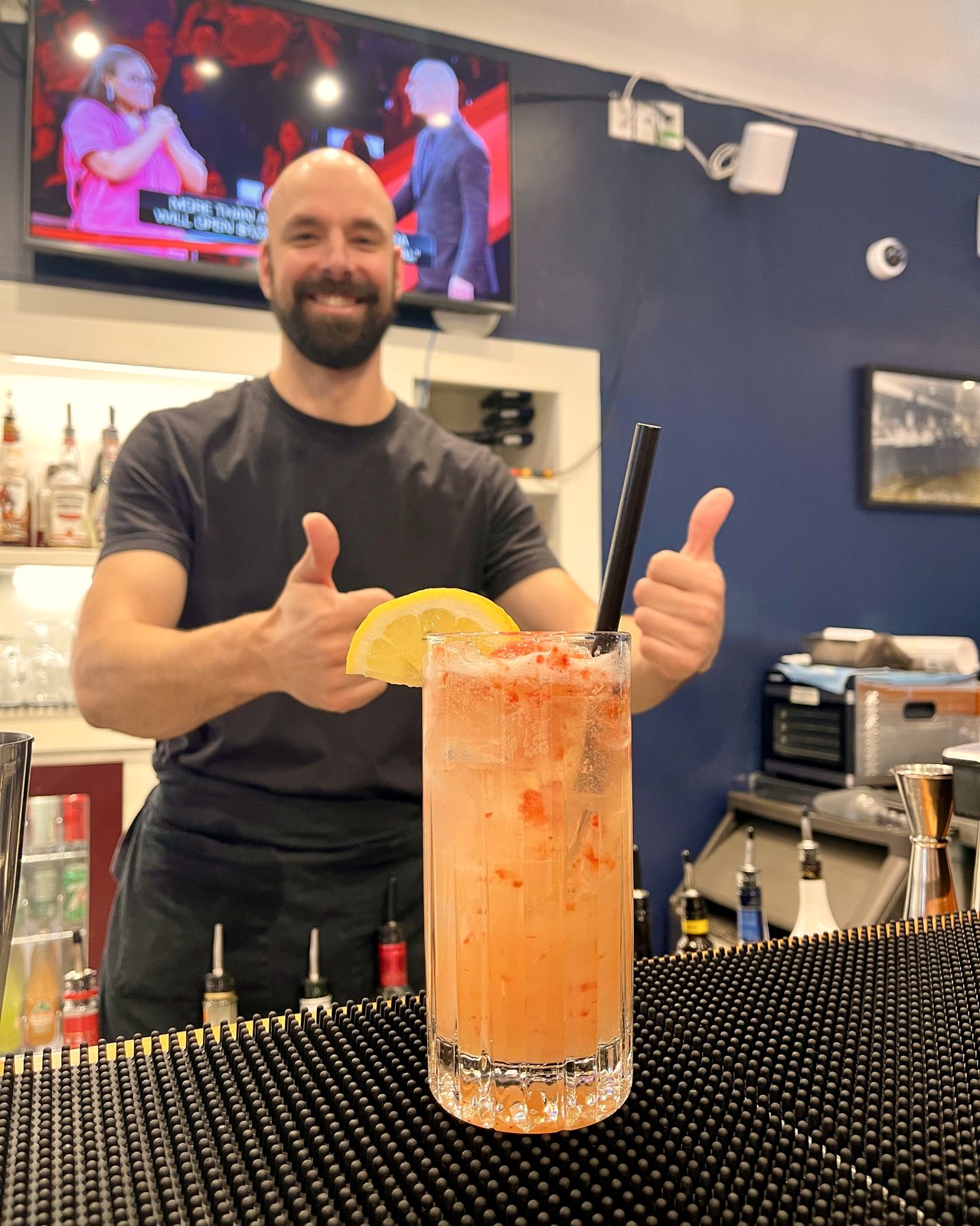 Bartender giving a thumbs up behind a signature cocktail at OV Burger Bar in Prince Rupert, BC