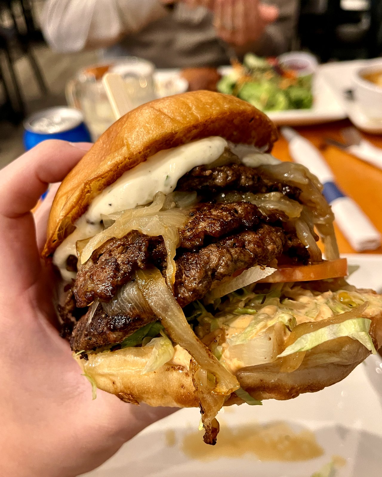 A guest holding a double smash burger with caramelized onions, garlic aioli, and OV burger sauce at OV Burger Bar in Prince Rupert, BC